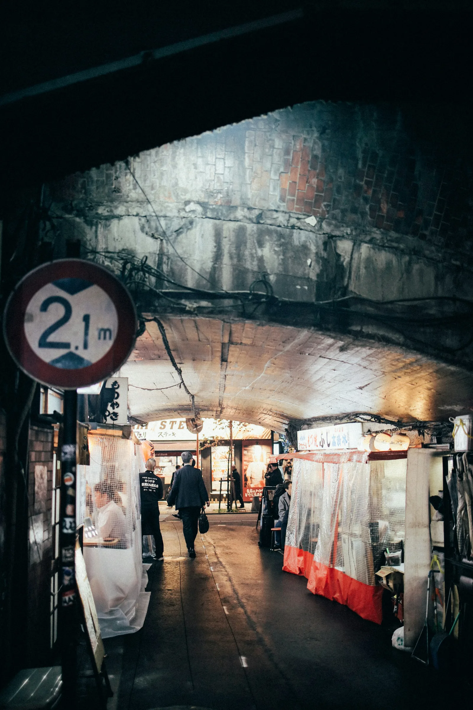 People walking through a narrow Tokyo alley lined with shops
