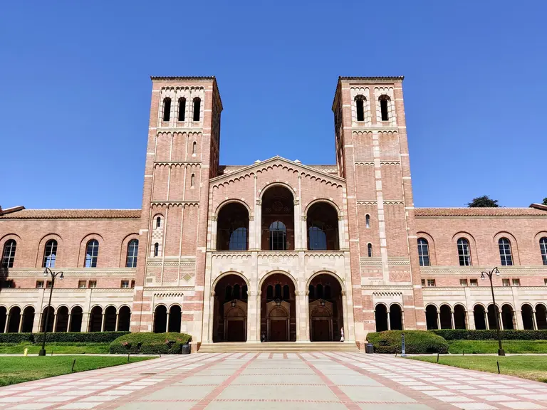 Royce Hall and its brick plaza under a clear blue sky.
