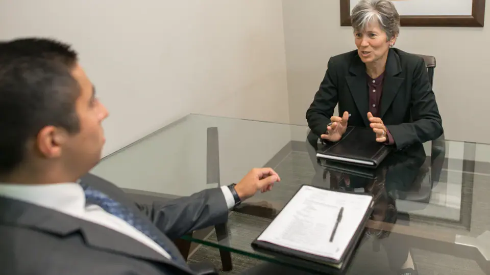 Two people seated across a table during a job interview.