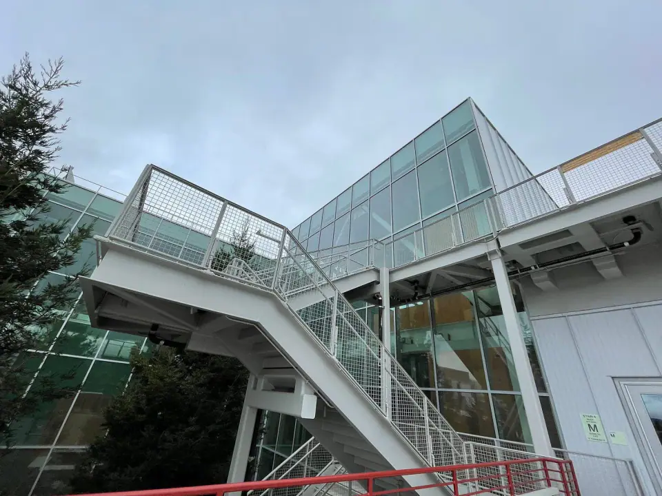 A glass stairway and elevated walkway seen from below.