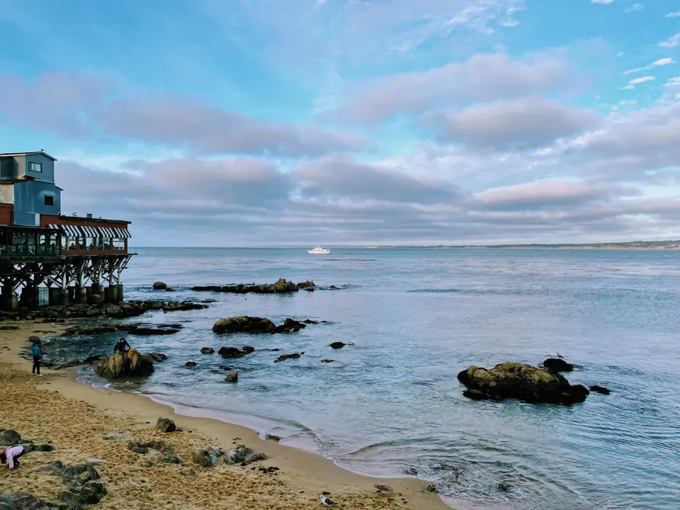 A rocky shoreline and pier beneath a blue sky.
