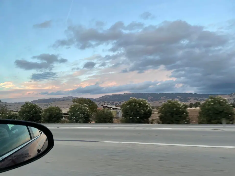 Distant mountains and evening clouds seen from a moving car.